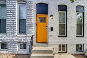 a orange door on a white building with stairs at Newly Renovated Abode with Patio in Baltimore! in Baltimore