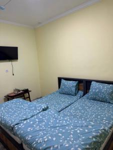 a bedroom with two beds with blue sheets and a television at ADORA HOSTEl in Tashkent +6 photos