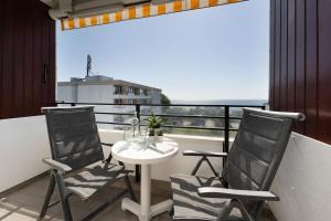 ein Balkon mit drei Stühlen und einem Tisch mit Aussicht in der Unterkunft Haus Meeresblick Wohnung 79 in Kellenhusen + 29 Fotos