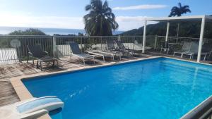 a large blue swimming pool with chairs and a deck at Oasis Grande Anse in Deshaies