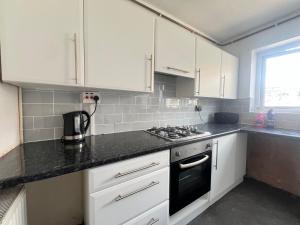 a kitchen with white cabinets and a black counter top at Spacious House Close to Central Manchester With Free Parking in Manchester