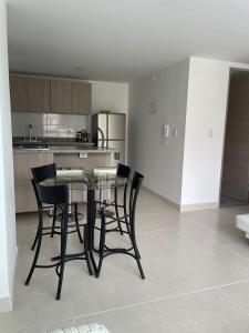 a kitchen with a table and black chairs in a room at CC Fundadores, cerca sector el Cable y CC Mall Plaza in Manizales +2 photos