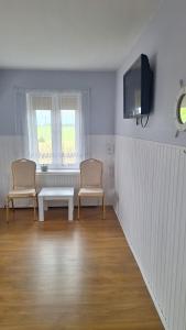 a room with two chairs and a table and a tv at Agroturystyka nad stawem Mazuchówka in Wydminy