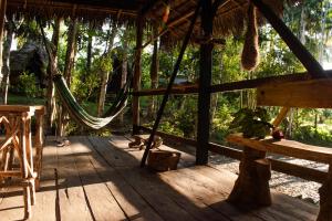 a wooden porch with a hammock in a forest at Jungle Cabin - Satori Natural in Puerto Nariño