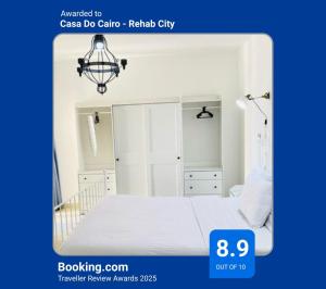 een witte slaapkamer met een bed en een kroonluchter bij Casa Do Cairo - Rehab City in Caïro