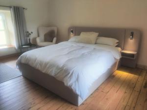 a large white bed in a bedroom with a chair at The Home House in Plumb Bridge