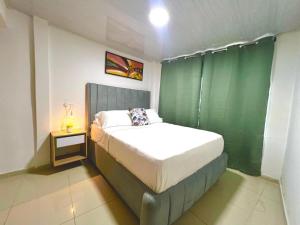 ein Schlafzimmer mit einem Bett und einer grünen Wand in der Unterkunft Increible Apto 10Min Base Aérea - Aquaparque Caña in Cali + 11 Fotos