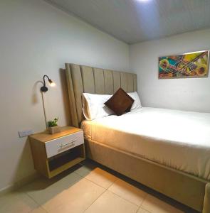 ein Schlafzimmer mit einem Bett und einem Nachttisch mit einer Lampe in der Unterkunft Increible Apto 10Min Base Aérea - Aquaparque Caña in Cali