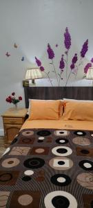 1 dormitorio con 1 cama con flores púrpuras en la pared en Hospedaje CASA REAL, en Huancayo