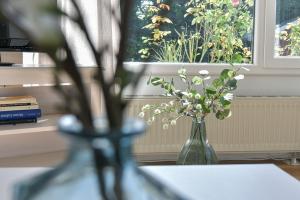 a vase of flowers sitting on a table with a window at Am Schoor Bungalow 12 in Grömitz +21 photos