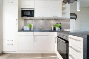 a white kitchen with white cabinets and black appliances at Strandresidenz Vogelflug App 8 in Fehmarnsund