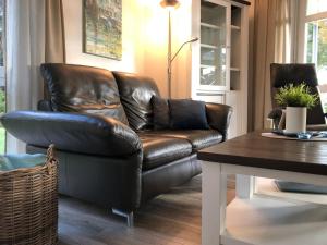 un sofá de cuero en una sala de estar con mesa en Bürgermeister-Fox 44a An der Waterkant, en Neue Tiefe Fehmarn