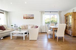 a living room with white furniture and a table at Bungalow Zwergenweg 2b in Grömnitzerhagen