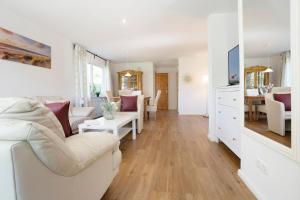 a living room with white furniture and a dining room at Bungalow Zwergenweg 2b in Grömnitzerhagen