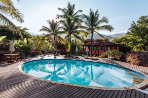 a swimming pool on a wooden deck with palm trees at Pousada Vila das Pedras in Ilhabela