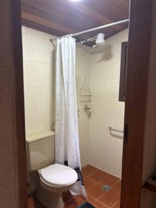 a bathroom with a toilet and a shower curtain at Pousada Cabanas do Visconde in Visconde De Maua