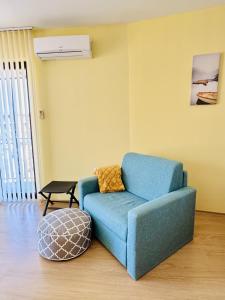 sala de estar con silla azul y reposapiés en Апартамент “Централ” / Central, en Balchik 35 fotos más
