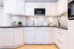 a white kitchen with white cabinets and a microwave at Aloha Suite in Fehmarn