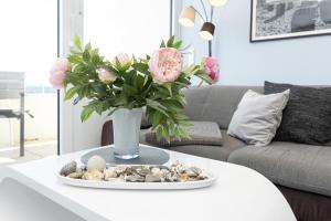 a vase with pink roses and rocks on a table at Aloha Suite in Fehmarn