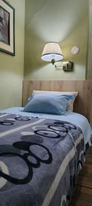 Una cama con una manta azul y una lámpara encima. en Hospedaje CASA REAL, en Huancayo
