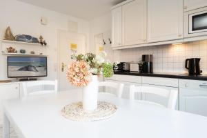 a white kitchen with a white table with a vase with flowers at Seepferdchen Wulkje in Hansaland