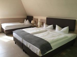 - une chambre avec 2 lits dotés de draps et d'oreillers blancs dans l'établissement Hotel Landsberg, à Landsberg
