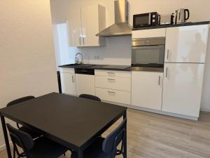 a kitchen with a black table and a white refrigerator at Stilvolles Apartment Royal Zentral Ruhig & Parkplatz inkl in Gelsenkirchen +24 photos