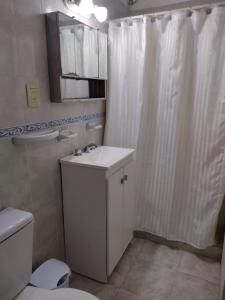 La salle de bains est pourvue d'un rideau de douche blanc et de toilettes. dans l'établissement Tu lugar en Colón, à Colón