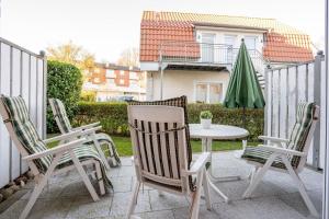 a patio with three chairs and a table and an umbrella at Villa Olga Wohnung 3 in Grömitz