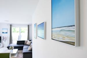 a living room with a blue couch and paintings on the wall at Wohnung 2 in Haffkrug