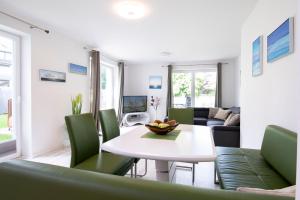 a living room with a white table and green chairs at Wohnung 2 in Haffkrug +17 photos