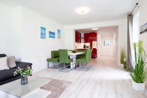 a living room with a table and green chairs at Wohnung 2 in Haffkrug