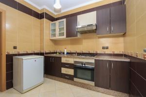 a kitchen with brown cabinets and a white refrigerator at Appartement avec piscine dans une résidence fermée in Tangier
