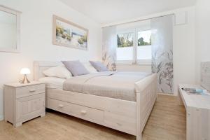 a white bedroom with a bed and a window at Brenkenhagener Weg 8-10 Wohnung 1 in Körnick