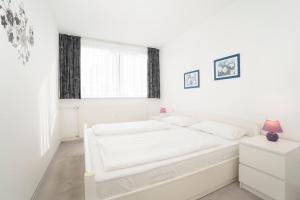 Un dormitorio blanco con una cama blanca y una ventana. en Haus Meeresblick Findling, en Kellenhusen