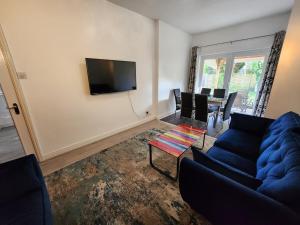 un soggiorno con un divano blu e una TV di Newly Refurbished 3 Bedroom House with Lovely Garden a Bolton