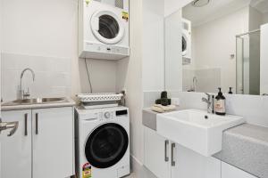 a white kitchen with a washing machine and a sink at Tranquil Tree Views 2 Bedroom 2 Bathroom Apartment in Perth