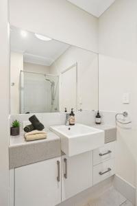 パースにあるTranquil Tree Views 2 Bedroom 2 Bathroom Apartmentの洗面台とシャワー付きの白いバスルーム