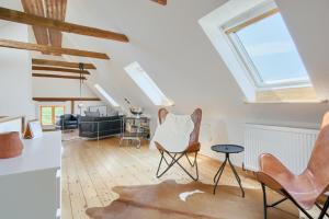 Una sala de estar abuhardillada con tragaluces y sillas. en Landhaus Auszeit, en Rüting