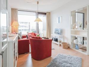 ein Wohnzimmer mit einem roten Stuhl und einem Sofa in der Unterkunft Haus Meeresblick Wohnung 24 in Kellenhusen