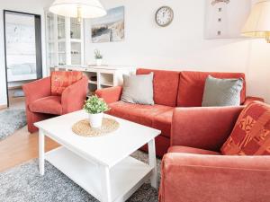 ein Wohnzimmer mit roten Sofas und einem weißen Tisch in der Unterkunft Haus Meeresblick Wohnung 24 in Kellenhusen