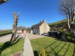 a house with a tree in front of a yard at Mc Courts Cottage in Hilltown
