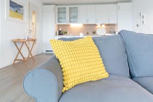 BosauにあるHaus Seeblick Bosau Maräneの青いソファーの上に黄色の枕が置かれたリビングルーム