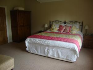 a bedroom with a large bed with pink and yellow pillows at The Paddock in Haverfordwest