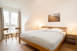 a white bedroom with a bed and a window at Ferienhaus Salomons Sonne in Kellenhusen