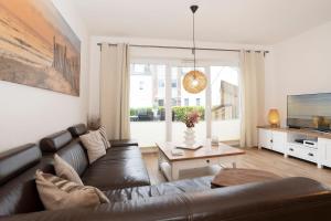 a living room with a leather couch and a television at Ferienhaus Salomons Sonne in Kellenhusen