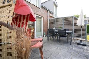 a patio with a table and chairs and an umbrella at Ferienhaus Salomons Sonne in Kellenhusen +42 photos