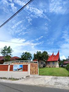 a house with a fence in front of a street at Rumah Gadang Puti Bungsu in Baso