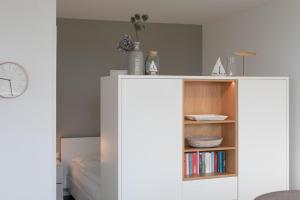 a white cabinet with a book shelf and a clock at Haus Vier Jahreszeiten De Lütte in Dahme +34 photos
