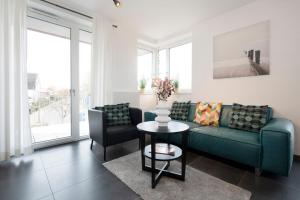 Una sala de estar con un sofá y dos sillas y una mesa. en KellenHus Wohnung 7, en Kellenhusen